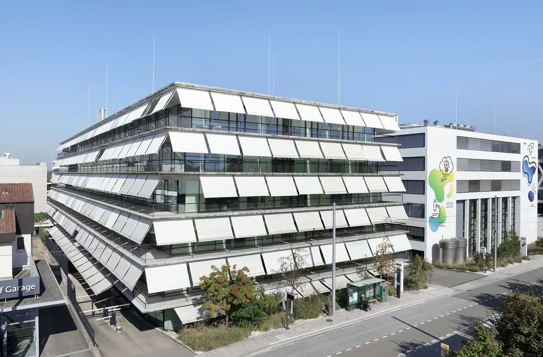 Das Gebäude H89 auf dem SONUVO-Campus in Allschwil von schräg oben, gestaffelte Fassade vor blauem Himmel