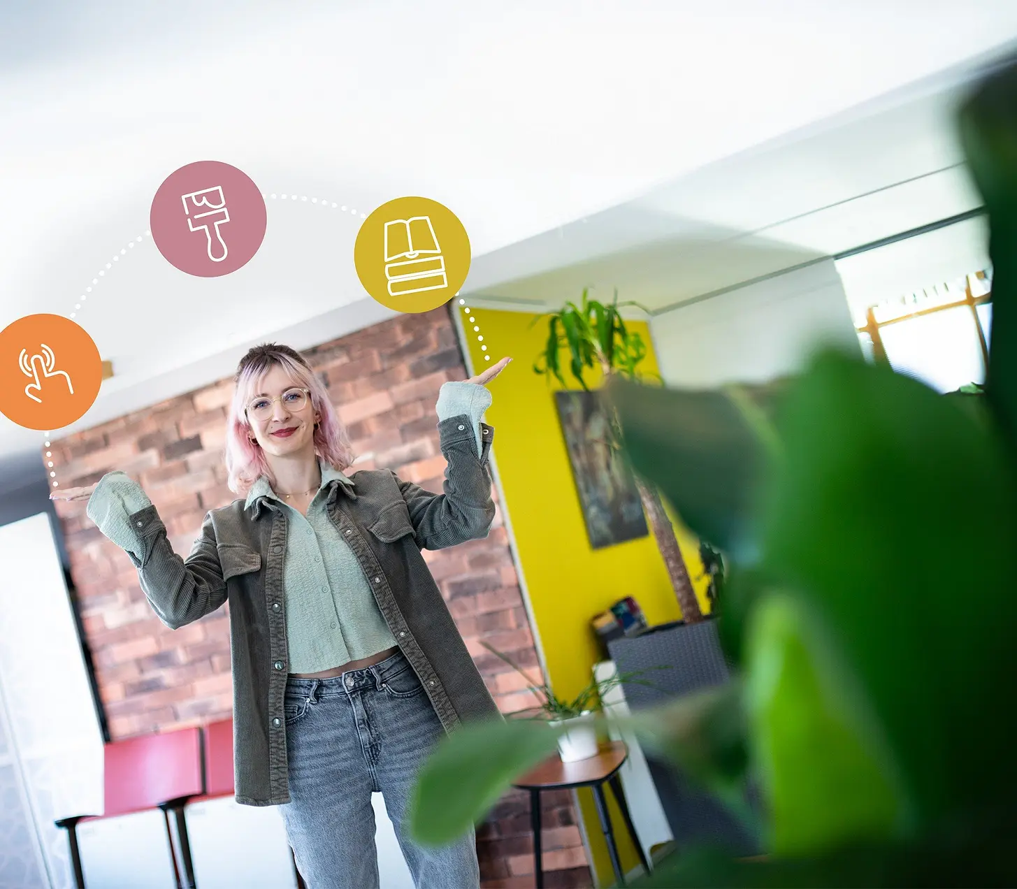 Frau reckt im Büro die Arme hoch, darüber schweben Symbole für Gestaltung und Branding