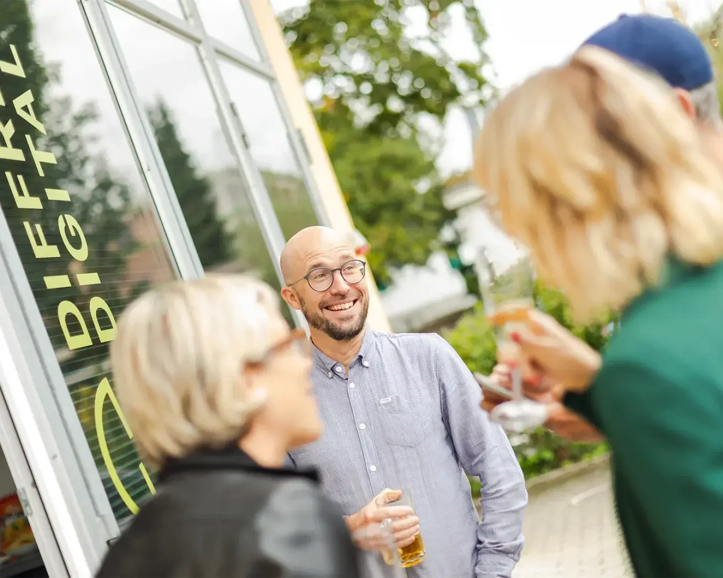 Gespräch bei einem Bier vor der beschrifteten Glasfront von diffrent digital