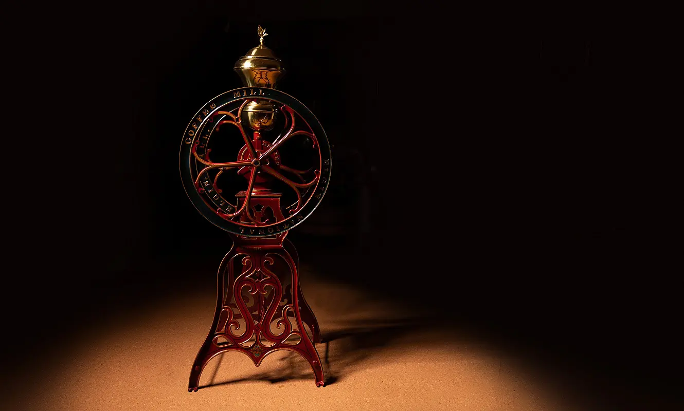 Historische rote Kaffeemühle mit Messingdeckel im Lichtkegel