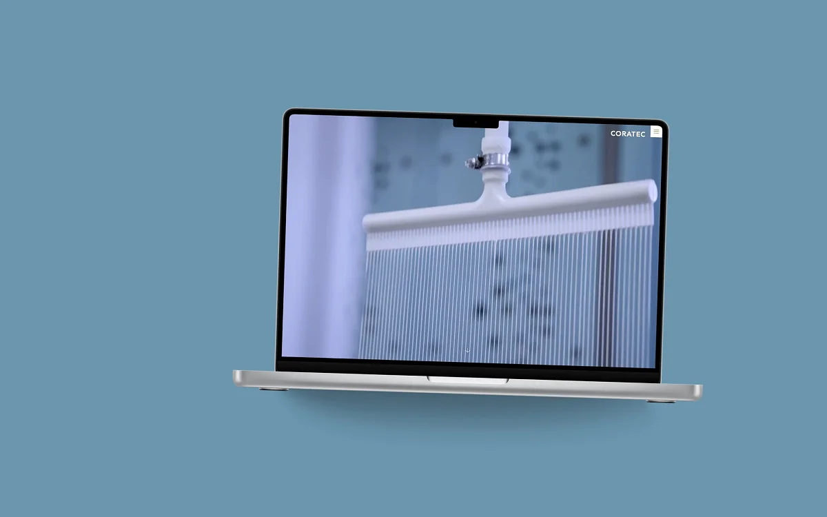 Startseite von Coratec AG auf einem MacBook, vor einer Fläche in der Kundenfarbe