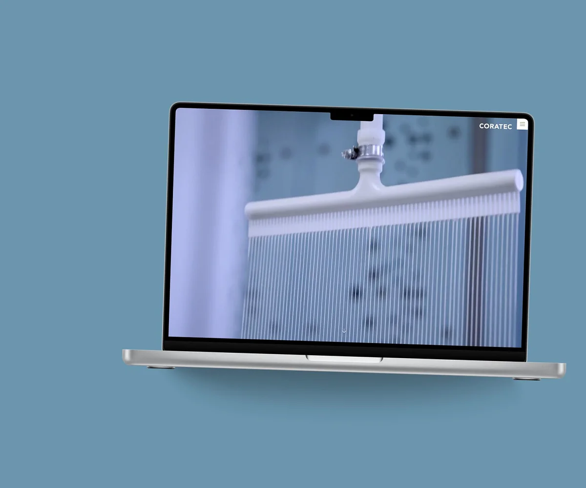 Startseite von Coratec AG auf einem MacBook, vor einer Fläche in der Kundenfarbe