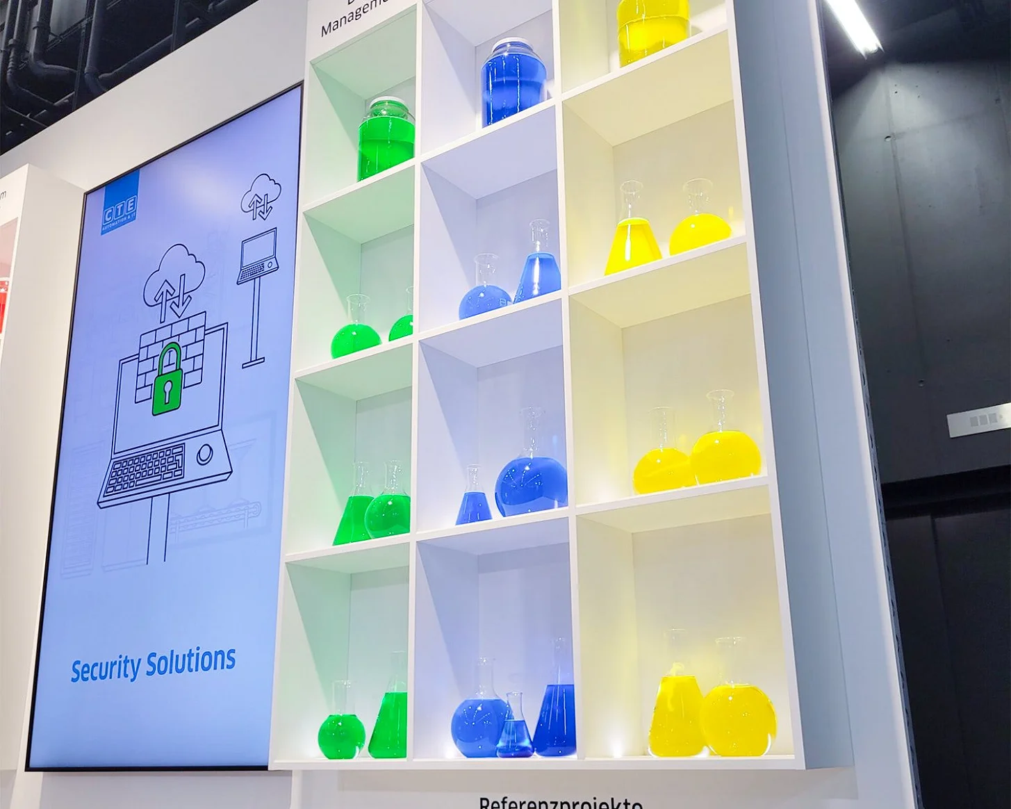 Die Regalwand am CTE-Stand: Leistungsfelder Data Management, Security Solutions und IT Infrastructure als grün, blau und gelb gefüllte Laborgefässe, darunter die Referenzprojekte als Reagenzgläser