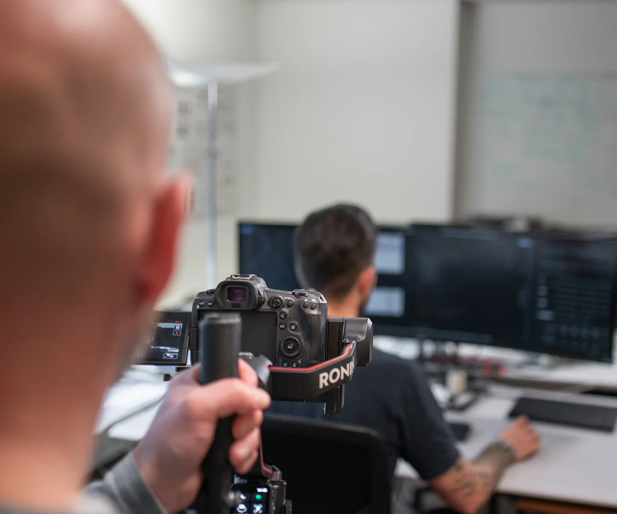Making-of beim Dreh: Blick über die Schulter auf Kamera und Gimbal, dahinter ein Mitarbeiter am Arbeitsplatz
