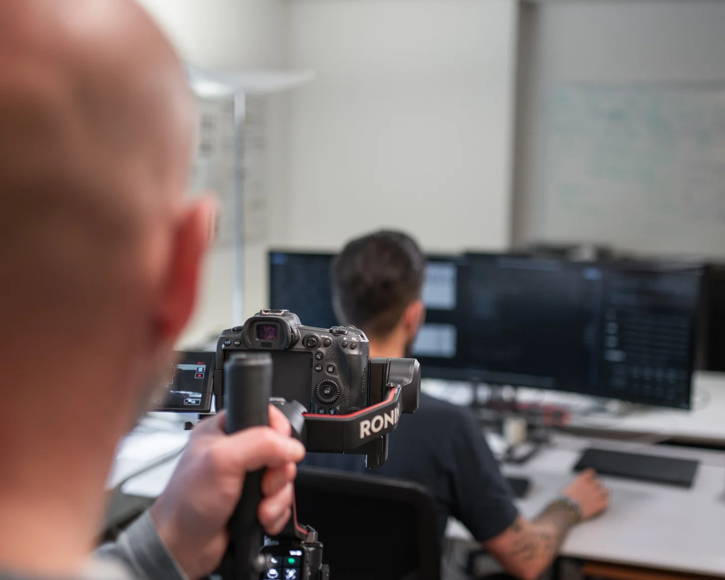 Making-of beim Dreh: Blick über die Schulter auf Kamera und Gimbal, dahinter ein Mitarbeiter am Arbeitsplatz