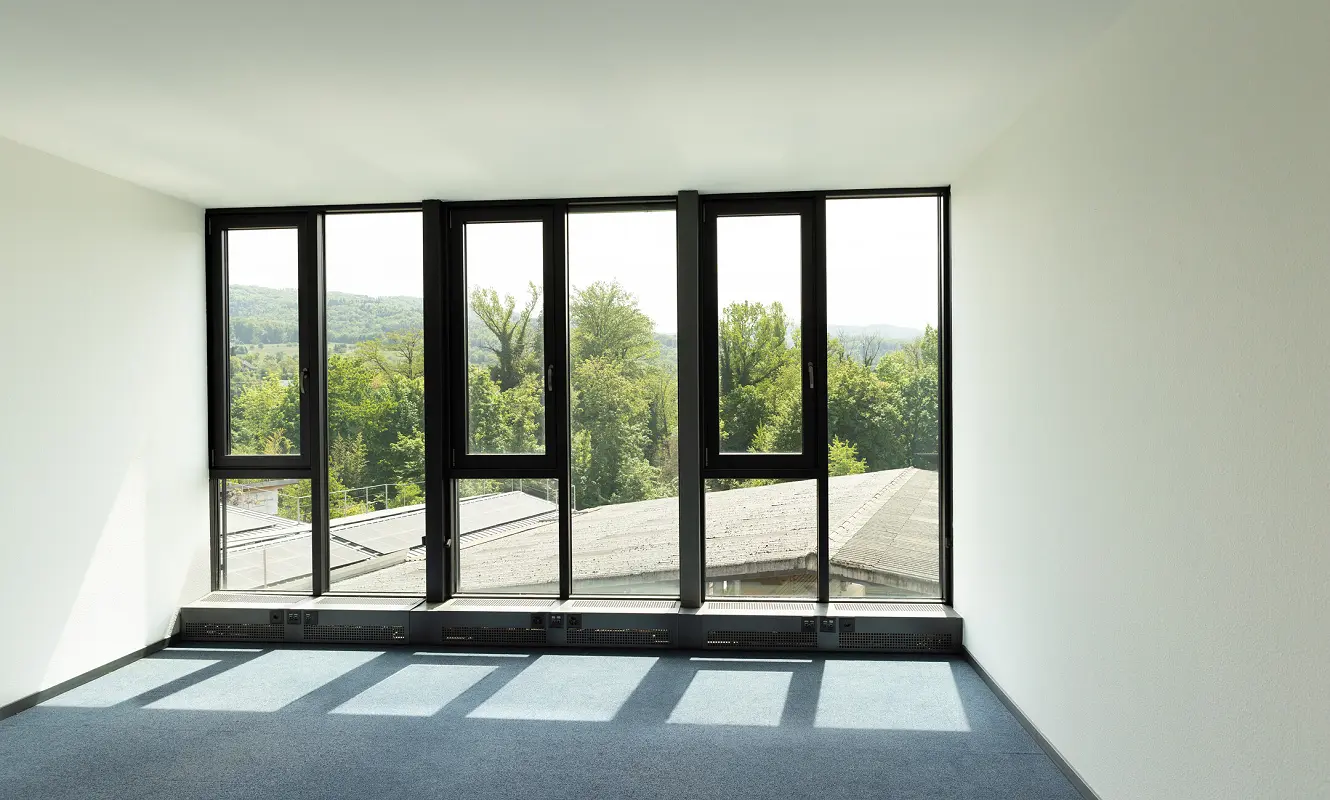 Leerer Raum mit bodentiefer Fensterfront und Blick ins Grüne
