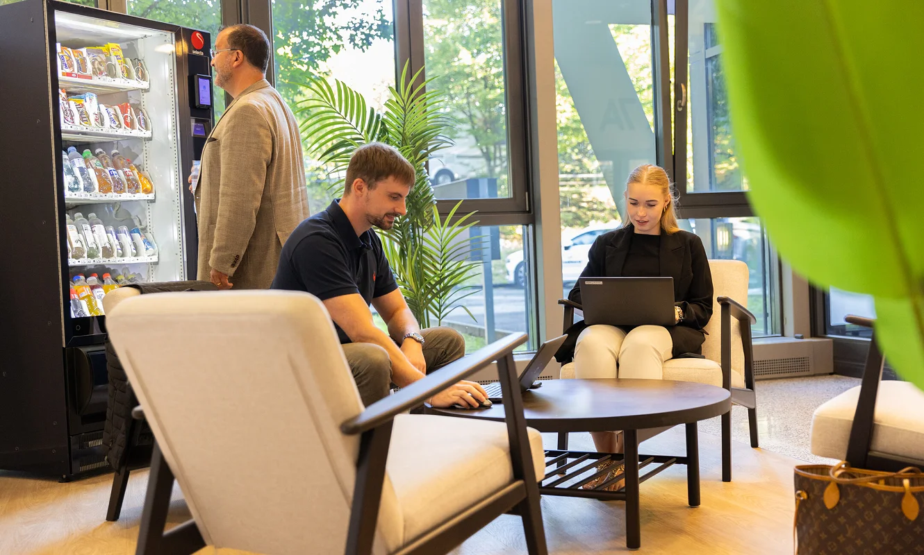 Zwei Personen in der Lounge mit Sesseln, Laptop und Snackautomat