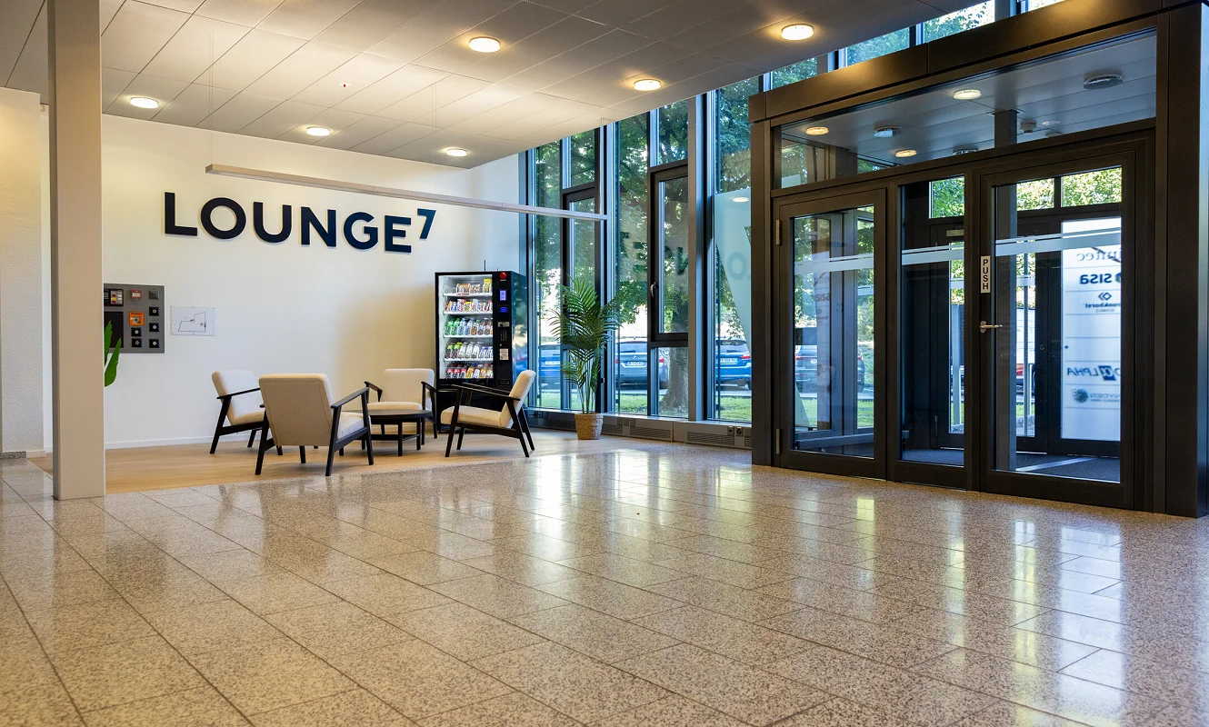 Eingangshalle mit Beschriftung «Lounge7», Sitzgruppe und Snackautomat