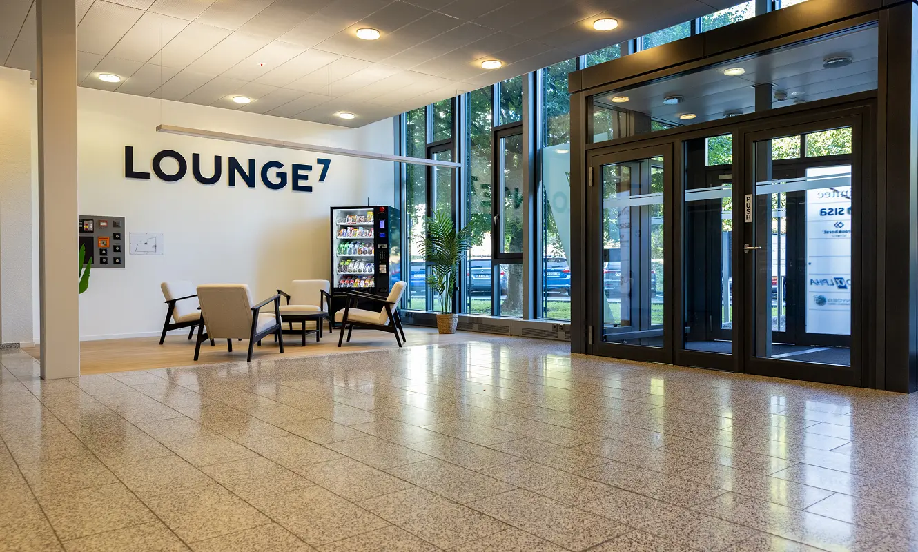 Eingangshalle mit Beschriftung «Lounge7», Sitzgruppe und Snackautomat