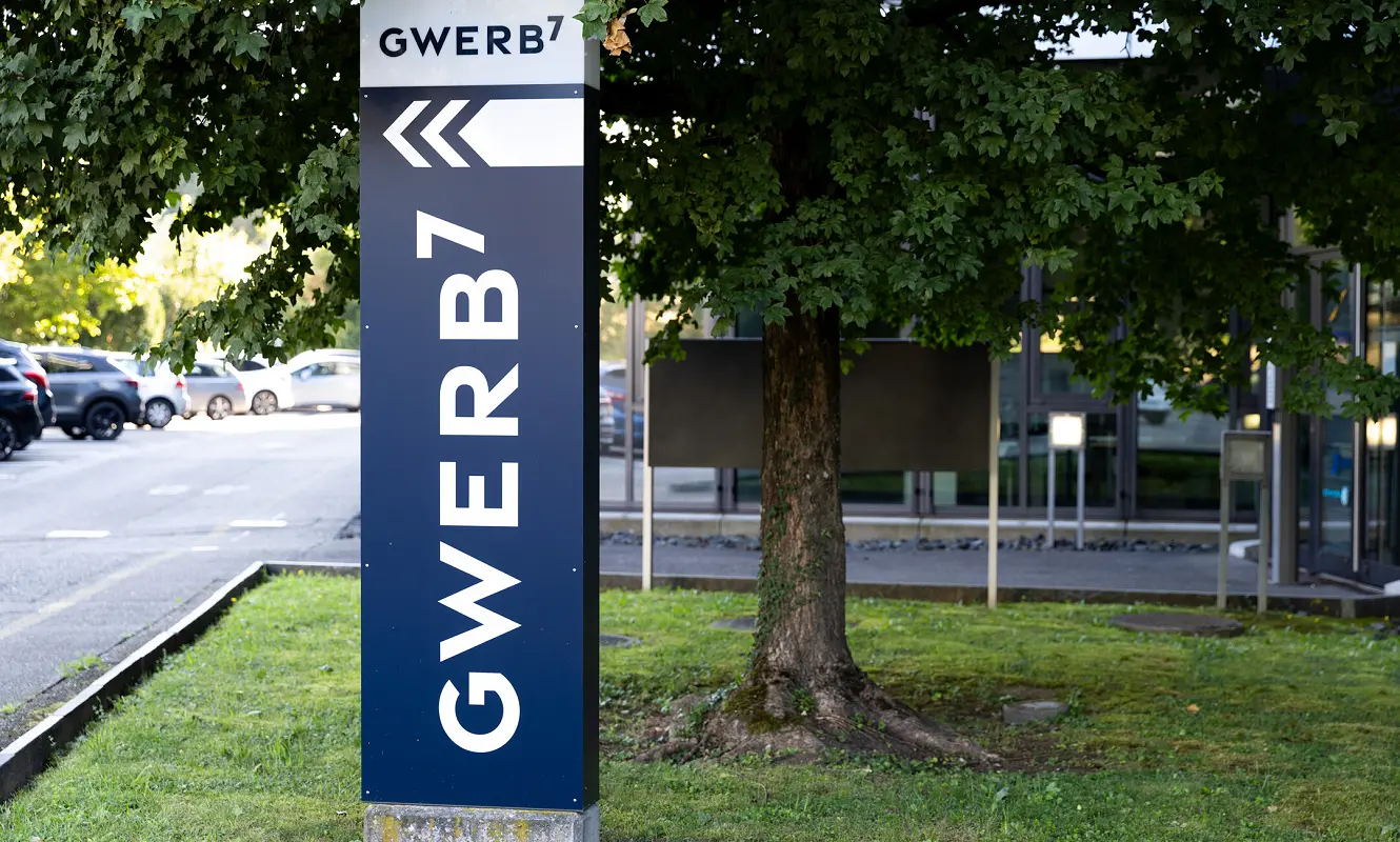 Pylon mit GWERB7-Beschriftung und Richtungspfeil vor dem Gebäude