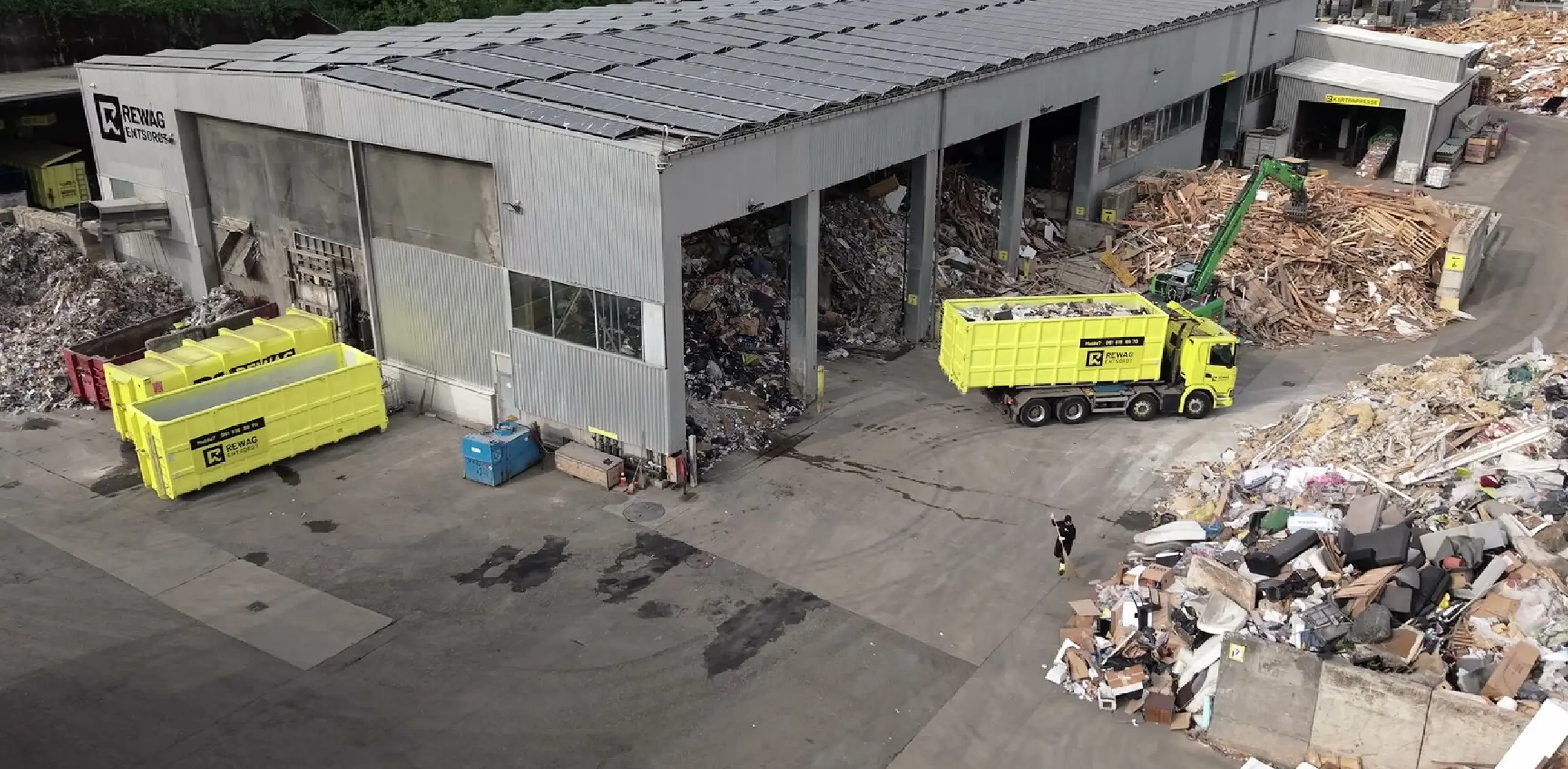 Standbild aus dem Headerfilm: Luftaufnahme des Areals mit Lastwagen und Mulden vor der Sortierhalle