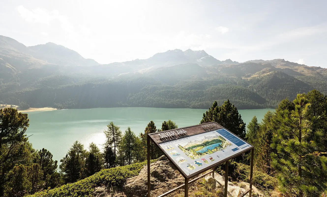 Panoramatafel im Gegenlicht über dem Silvaplanersee mit Bergkette