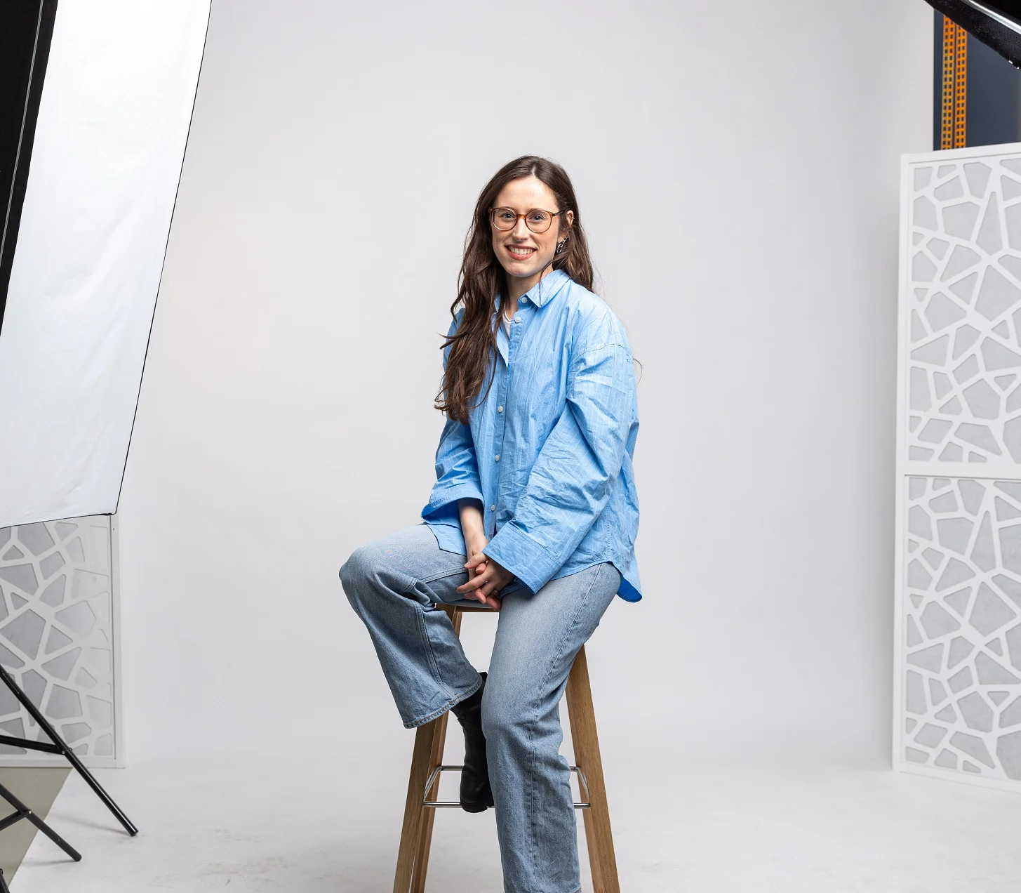 Melina sitzt im Fotostudio auf einem Hocker zwischen den Studioleuchten