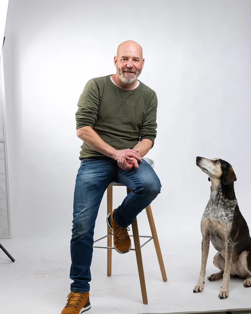 Roger auf dem Hocker im Fotostudio, daneben Inge zwischen den Studioleuchten
